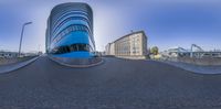 a curved building sits on the side of the road with buildings behind it in the background