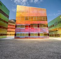 a building with multiple different colors of paint on it and windows that look like they are stacked