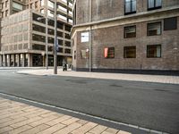 the side walk with the street next to it is empty with traffic lights on either side and buildings on the other side