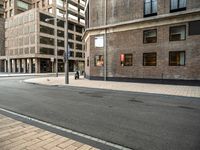 the side walk with the street next to it is empty with traffic lights on either side and buildings on the other side