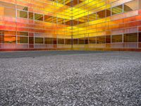 an empty courtyard that has a brightly colored facade in the middle of it, with a stone paved floor