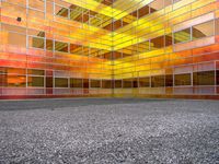 an empty courtyard that has a brightly colored facade in the middle of it, with a stone paved floor