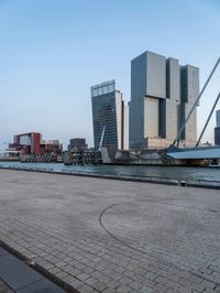 an empty pier with tall buildings in the background and people on the side walk across it