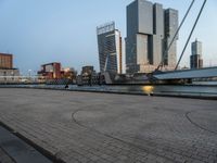 a bicycle parked in front of a bridge and some buildings in the background at dusk