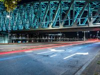 an empty city road in front of an illuminated bridge at night on a street corner