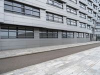 an empty sidewalk in front of a modern building on a sunny day with clouds in the distance