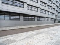 an empty sidewalk in front of a modern building on a sunny day with clouds in the distance