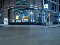 a lighted store sits outside a brown brick building in a city at night with no traffic