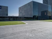 an intersection in the middle of an empty lot on a bright, sunny day with the windows of a large modern building reflecting the sky