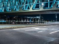 a night shot of an intersection with road signs, and a bridge in the background