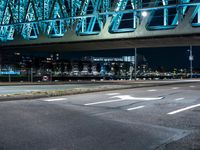 a night shot of an intersection with road signs, and a bridge in the background