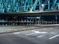 a night shot of an intersection with road signs, and a bridge in the background