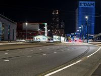 the street is empty at night with no traffic to the left and one end of it with lights coming from above