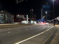 the street is empty at night with no traffic to the left and one end of it with lights coming from above