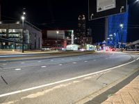 city scene at night time with tall buildings lit up by bright street lights and traffic on street