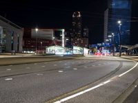 city scene at night time with tall buildings lit up by bright street lights and traffic on street