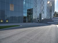 a skateboarder riding up the side of an empty road next to a large building