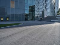 a skateboarder riding up the side of an empty road next to a large building