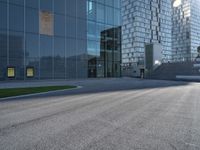 a skateboarder riding up the side of an empty road next to a large building