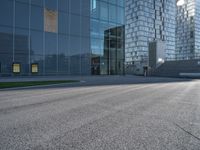 a skateboarder riding up the side of an empty road next to a large building