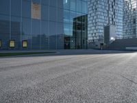 a skateboarder riding up the side of an empty road next to a large building