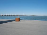 a view of a pier with a metal structure overlooking the water and a sail boat in the distance