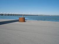 a view of a pier with a metal structure overlooking the water and a sail boat in the distance