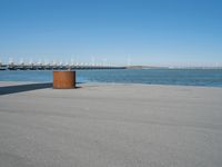 a view of a pier with a metal structure overlooking the water and a sail boat in the distance