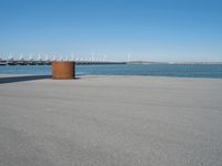 a view of a pier with a metal structure overlooking the water and a sail boat in the distance