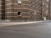 a man riding his bicycle through a city street past a brick building on the corner