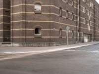 a man riding his bicycle through a city street past a brick building on the corner