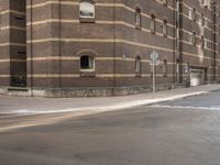 a man riding his bicycle through a city street past a brick building on the corner