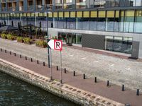 a small street sign near a waterway in front of large buildings next to a river