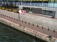 a small street sign near a waterway in front of large buildings next to a river