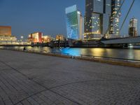 a river runs through a city near tall buildings and some benches in the foreground