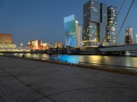 a river runs through a city near tall buildings and some benches in the foreground