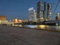 a river runs through a city near tall buildings and some benches in the foreground