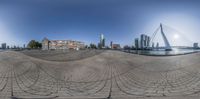 a fisheye lens view of an intersection with a circular pattern with the buildings, a bridge and other office blocks