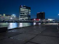 the view from an empty parking lot of a busy waterway in front of buildings and lights