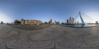 a fish eye lens captures an urban scene and riverbanks, looking up at the city and buildings