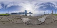 fisheye lens shows a city and water from a shore at sunset or sunrise time