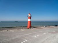 a man on a bike near the ocean by the water with a lighthouse at the edge