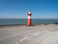 a man on a bike near the ocean by the water with a lighthouse at the edge