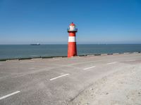 a man on a bike near the ocean by the water with a lighthouse at the edge