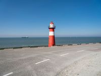 a man on a bike near the ocean by the water with a lighthouse at the edge