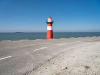 a man on a bike near the ocean by the water with a lighthouse at the edge