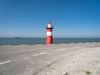 a man on a bike near the ocean by the water with a lighthouse at the edge