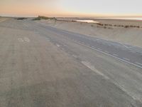 an aerial view of the desert road running on sand, overlooking the ocean and a sandy beach