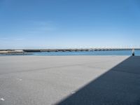 an empty beach with the sea and bridge in the back ground behind it, which are also a few small docks