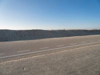 an empty, empty road with two vehicles parked in the dirt near a sand dune